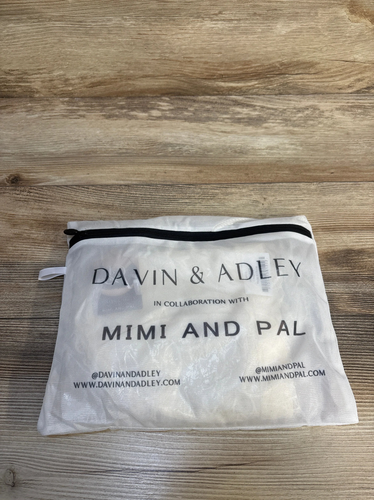 White mesh zipper pouch with Davin & Adley and Mimi and Pal branding on wood surface
