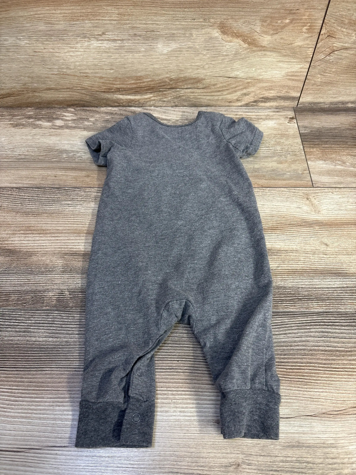 Back view of Disney Baby Mickey Mouse Jumpsuit Grey sz 3/6m showcasing heather grey short-sleeve romper with snap closure and cuffed ankles on wood plank floor