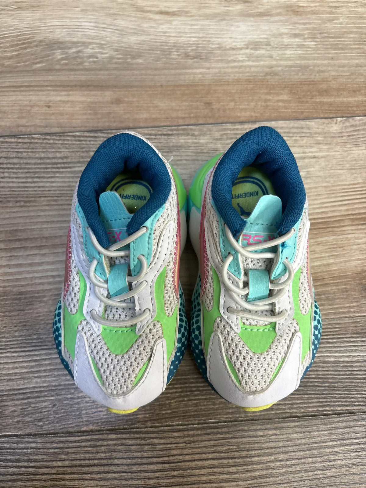 Front view of Puma Rs-X3 WR Sneakers in white size 5c showcasing white mesh uppers with green pink and teal color block details on wood plank backdrop
