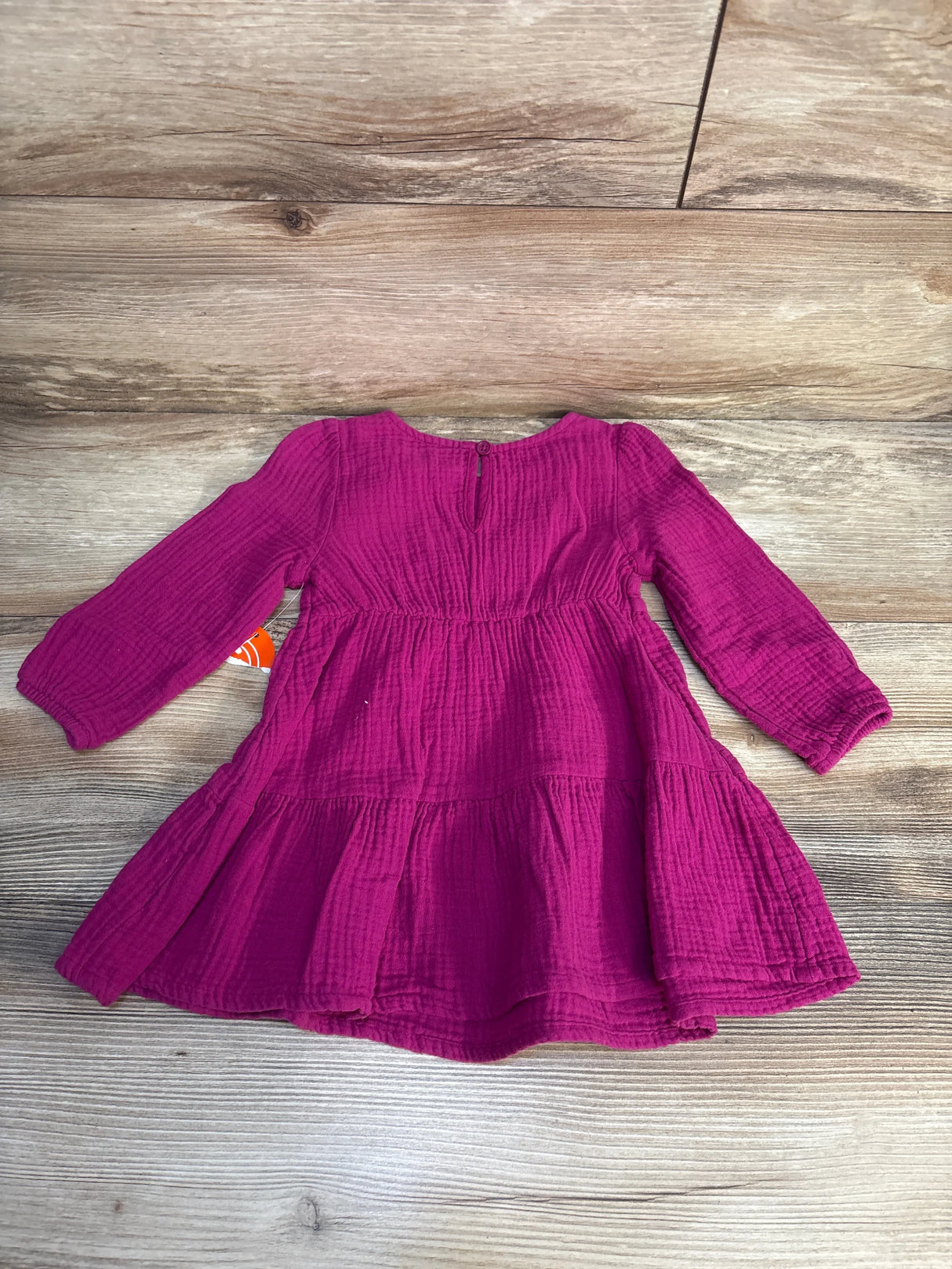 Magenta long sleeve toddler dress with textured cotton fabric on wooden background