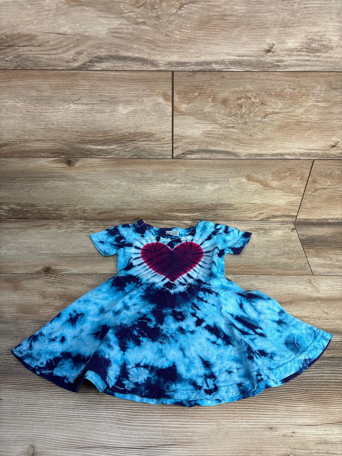 Front view of Dharma blue tie-dye heart dress, size 2T, showcasing a heart detail and flared skirt on a wood floor