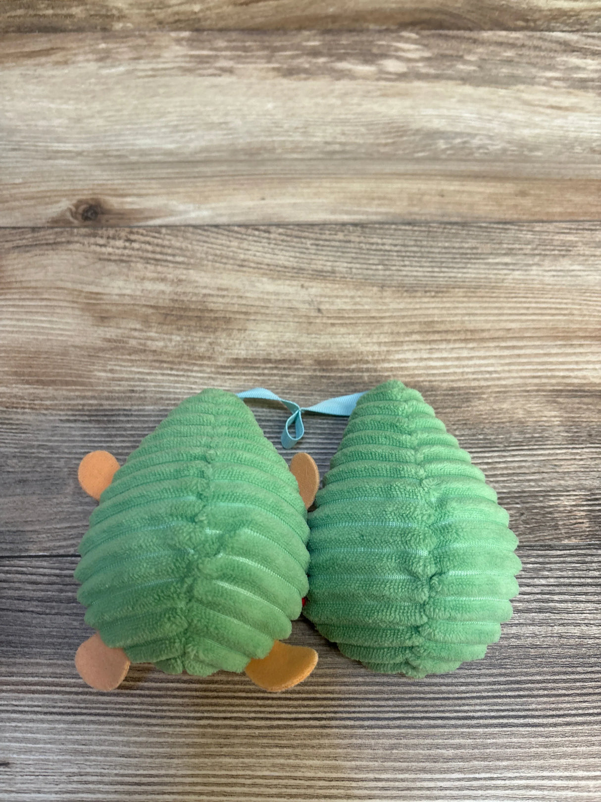 Green corduroy baby shoes with orange accents on wood floor