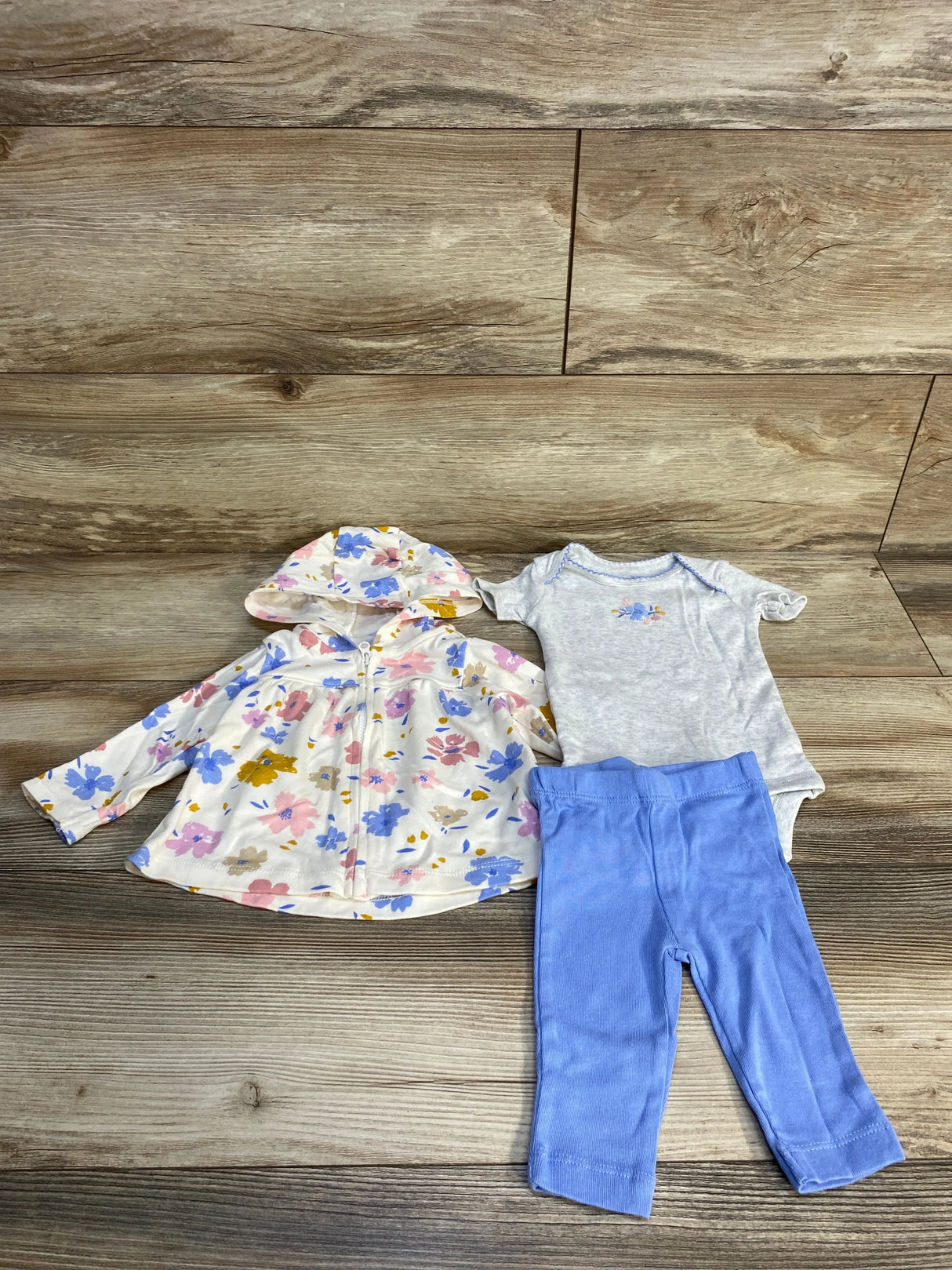 Toddler girl floral hooded jacket, gray bodysuit, and blue leggings set on wood background