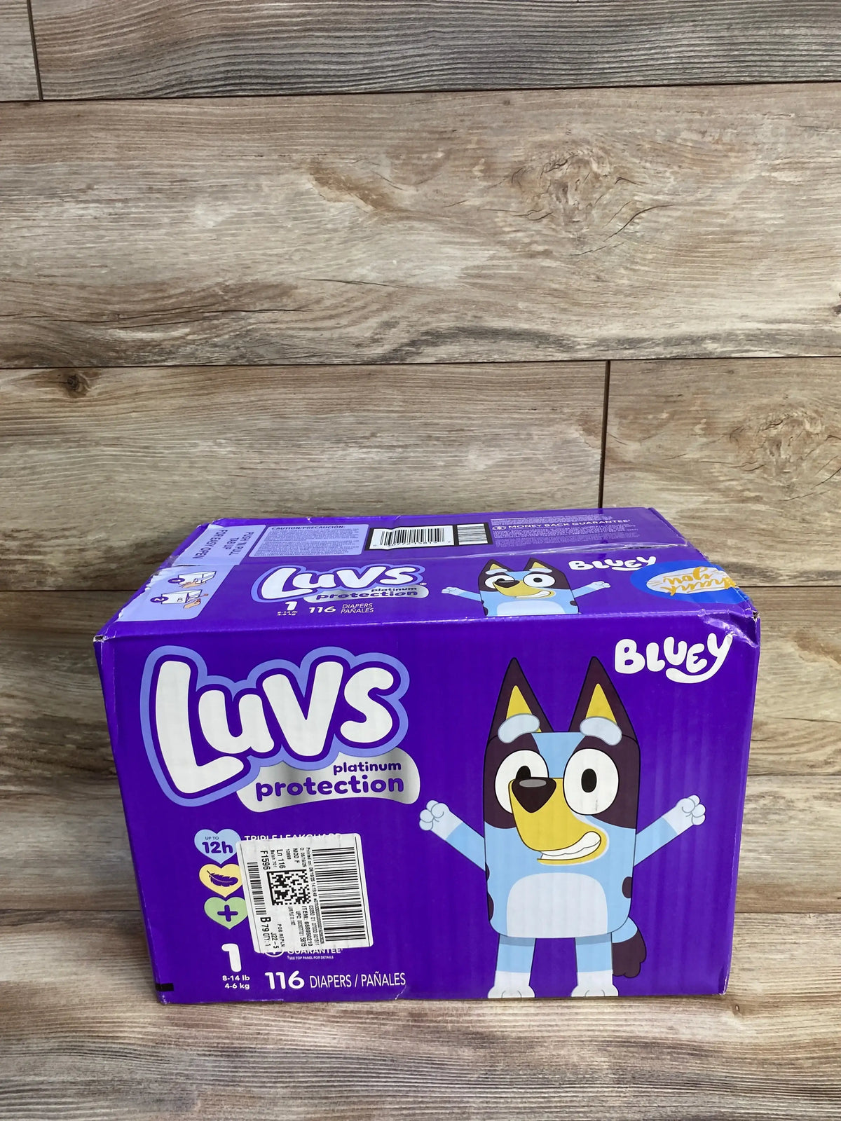 Front view of Luvs Platinum Protection size 1 diaper box 116 count Bluey design on wood background
