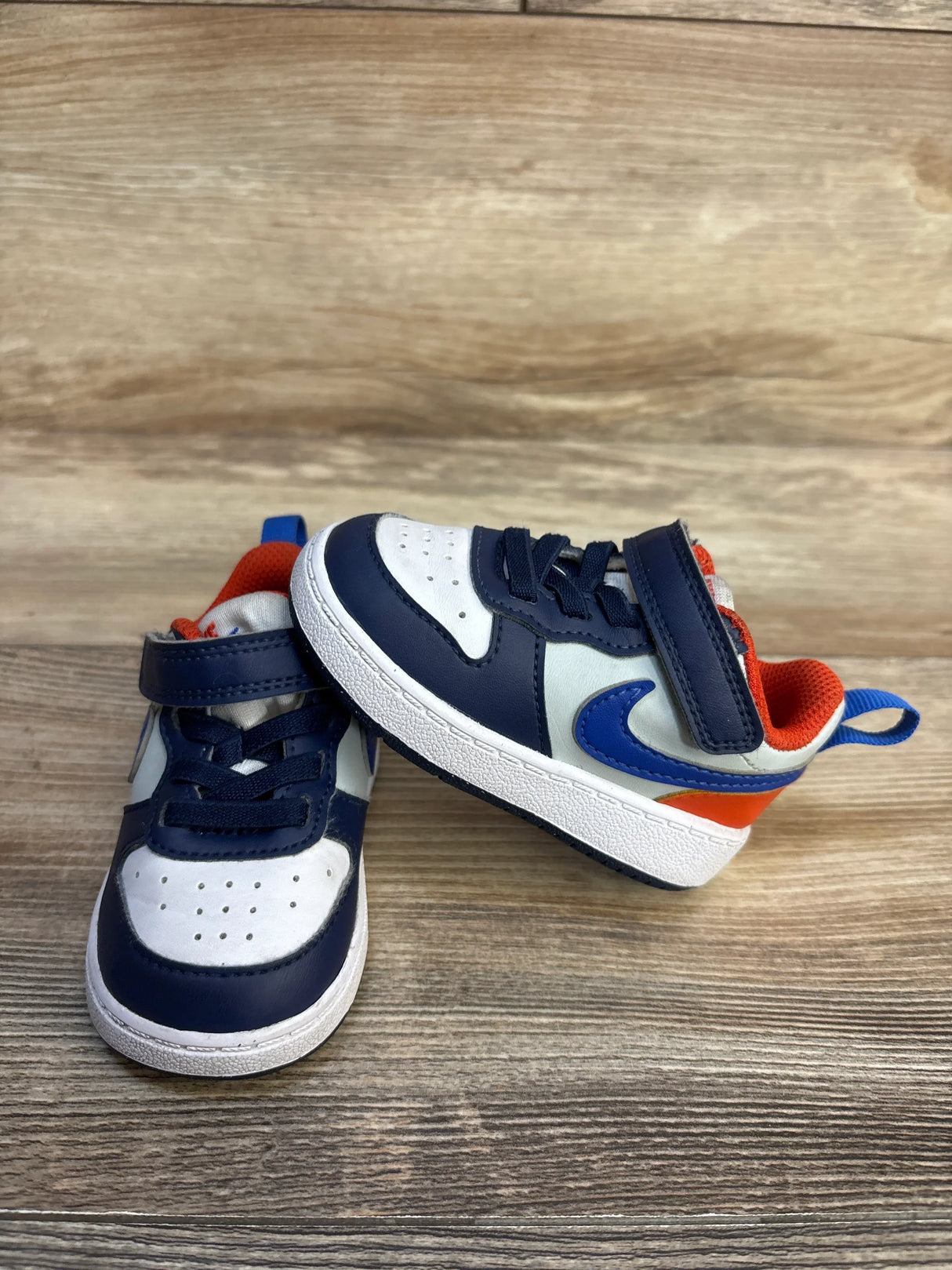 Side/front view of Nike Court Borough Low Recraft sneakers sz 4C in midnight navy, white and orange with Velcro strap and blue Swoosh