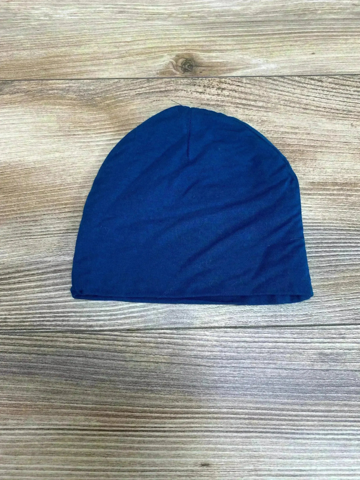 Flat lay of blue Posh P baby beanie size 6-9 months showing soft stretch knit and simple hem on wood background