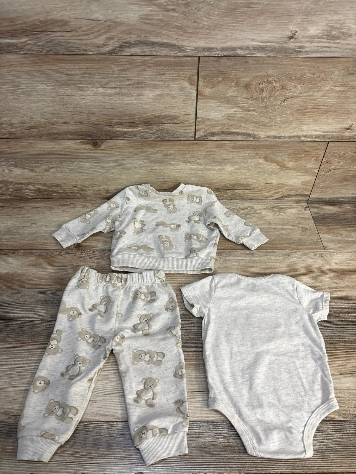 Baby boy 3-piece set with teddy bear print long sleeve top, pants, and plain onesie on wood floor