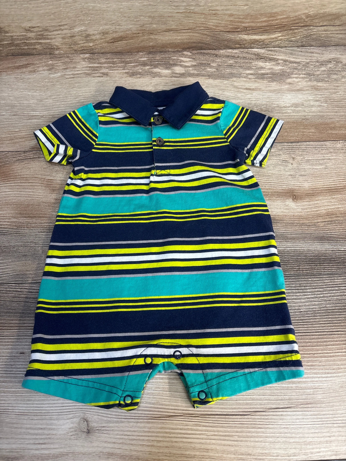 Striped short sleeve baby romper with collar, blue, green and yellow, laid on wood