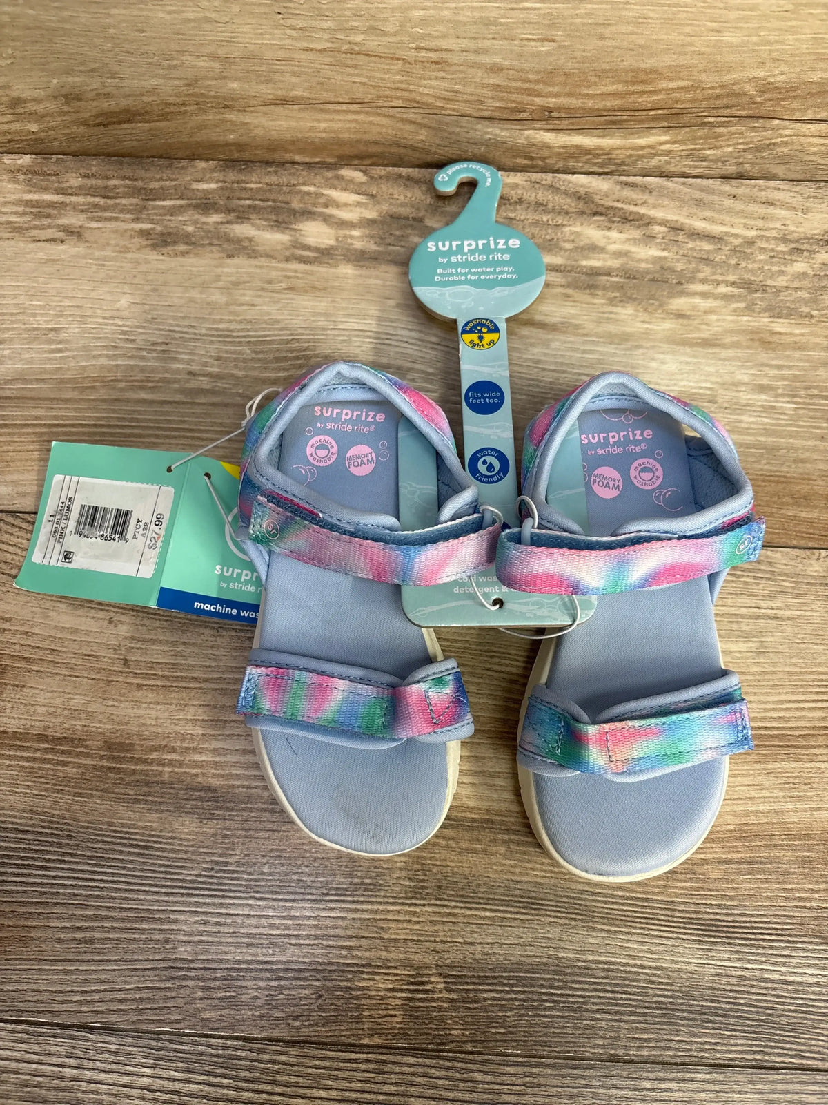 Top view of toddler blue Surprize light-up sandals showing pastel tie-dye Velcro straps and foam footbeds on wooden floor