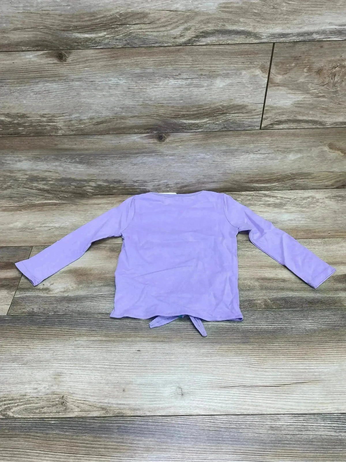Flat lay back view of Little Mermaid lavender toddler top size 3T showing long sleeves and front tie on wood floor background