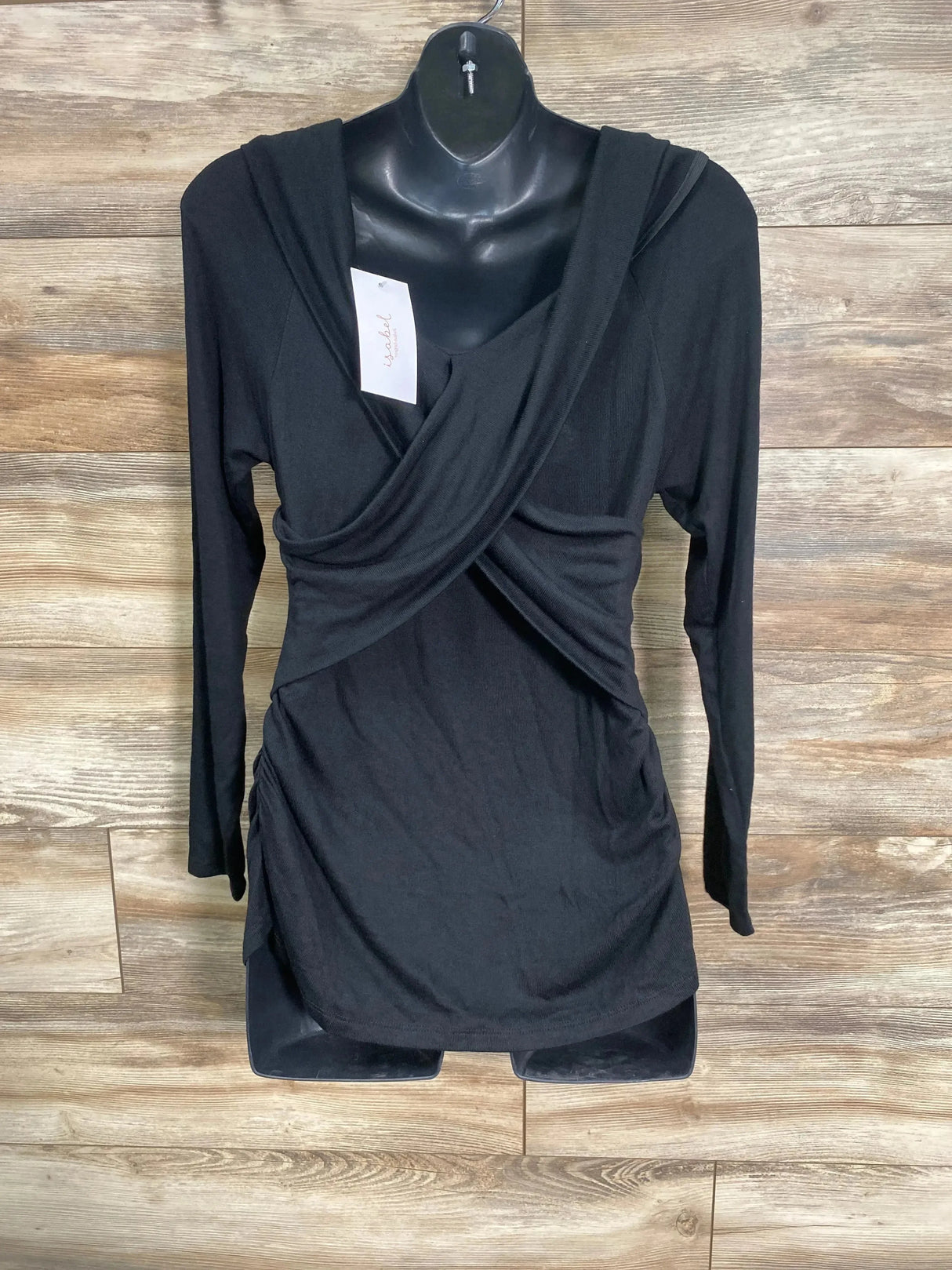 Front view of Isabel maternity cross-front black top with long sleeves, crossover neckline and side ruching on wood background
