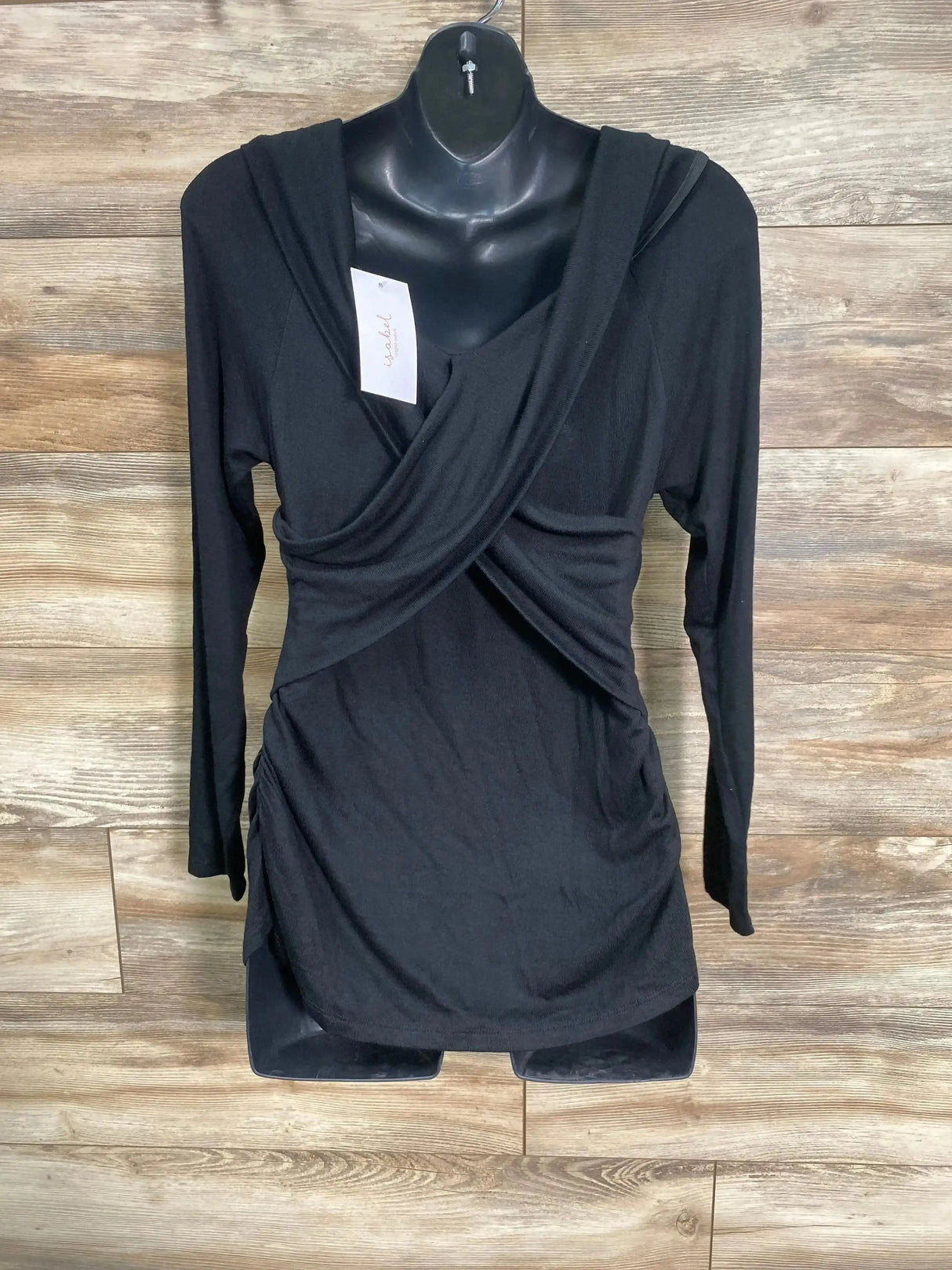 Front view of NEW Isabel maternity cross front top in black with long sleeves and ruched sides on dress form with hangtag on wood plank floor