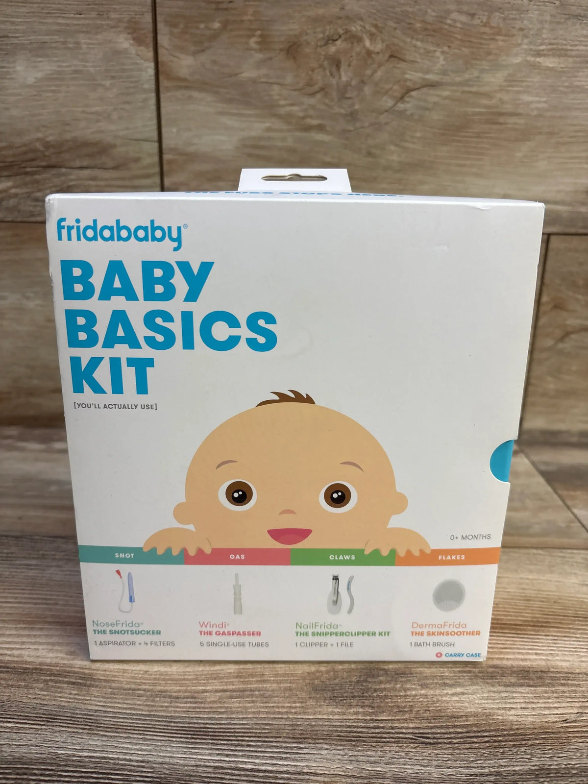 Front view of Frida Baby Basics Kit 14pc showcasing four labeled baby-care tools with a wood background