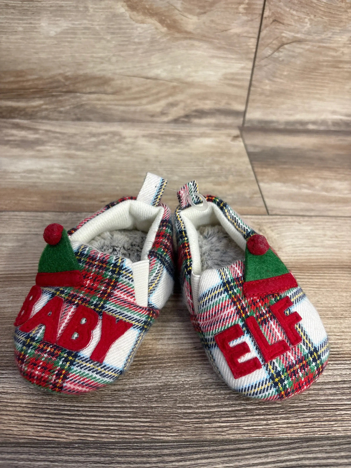 Baby elf shoes with plaid pattern, red 'BABY ELF' letters, and green hat tips on wood floor