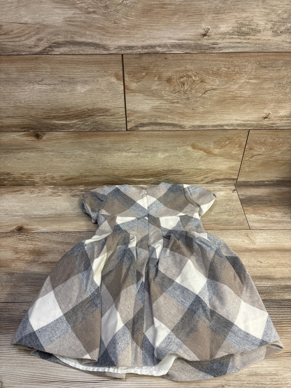 Flat-lay front view of Mayoral beige plaid wool-blend dress showcasing short sleeves and gathered skirt on a wooden floor