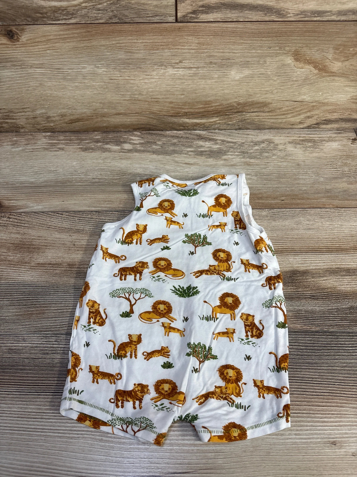 Flat lay of Mudpie white tank shortie romper showcasing all over lion print and sleeveless design on wood background