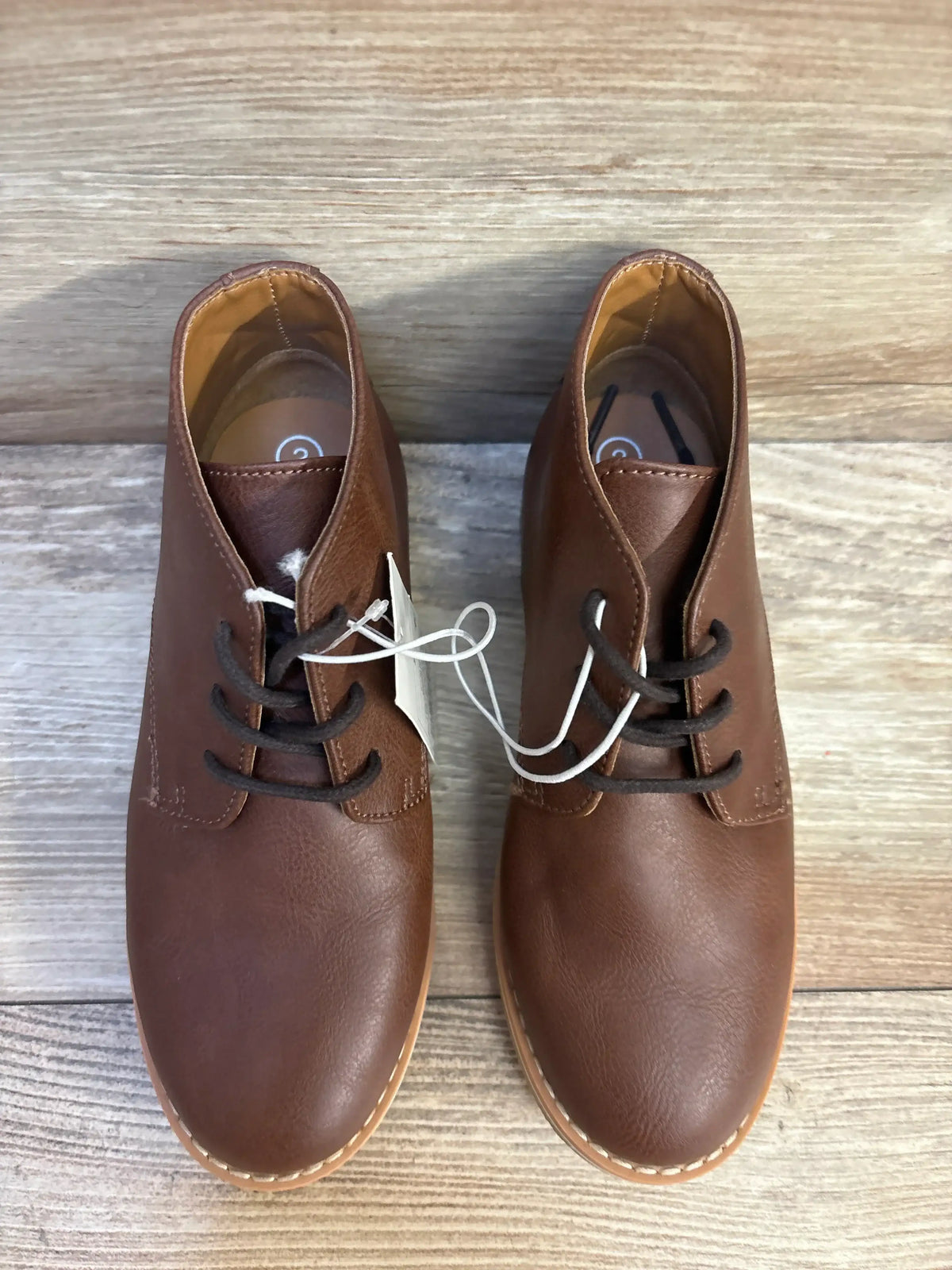 Top-down view of Cat & Jack Filip brown leather toddler boots, size 2Y, showing lace-up chukka style and stitched sole on wood floor