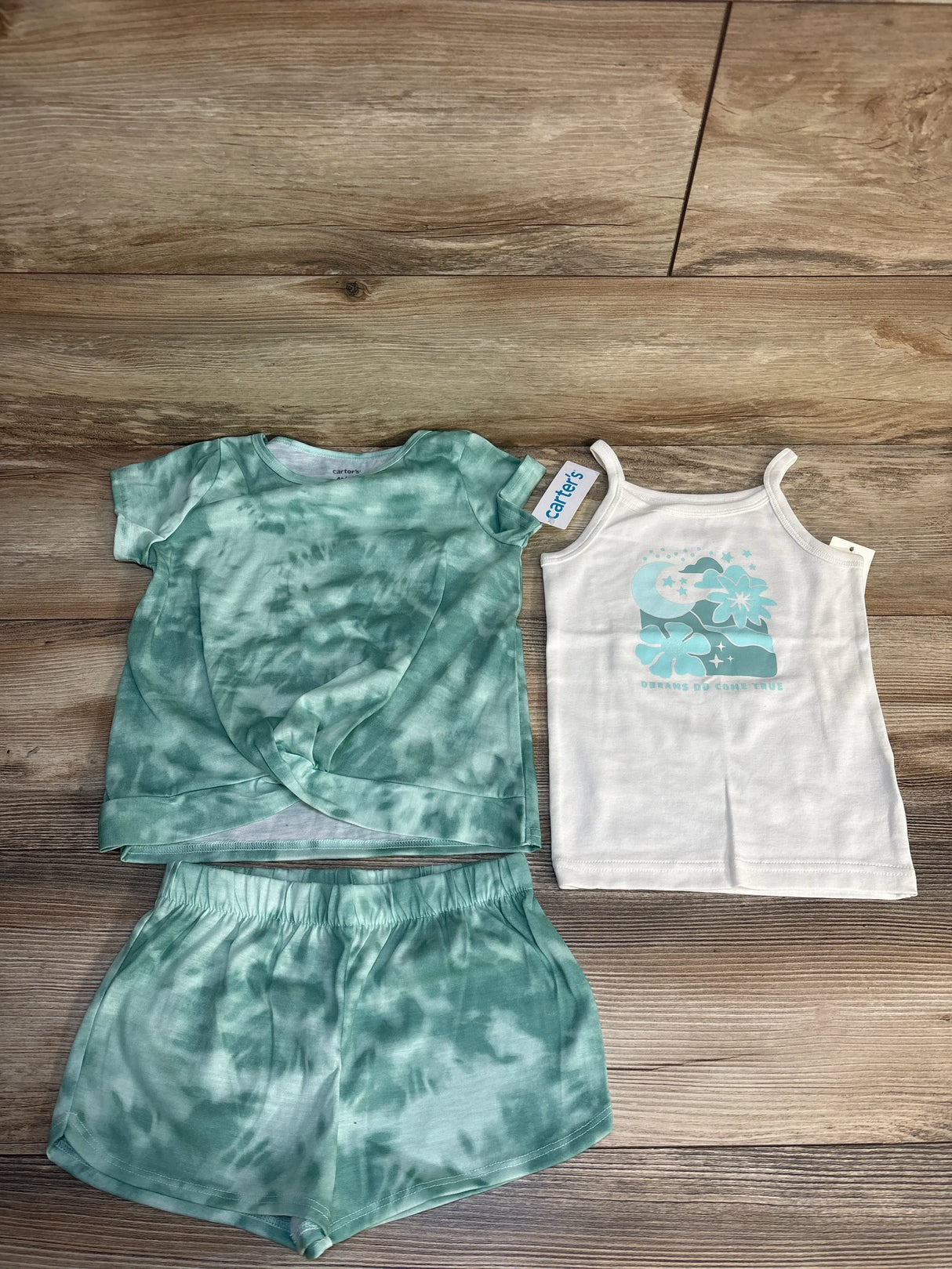 Green tie-dye kids shorts set with matching t-shirt and white tank top on wood floor