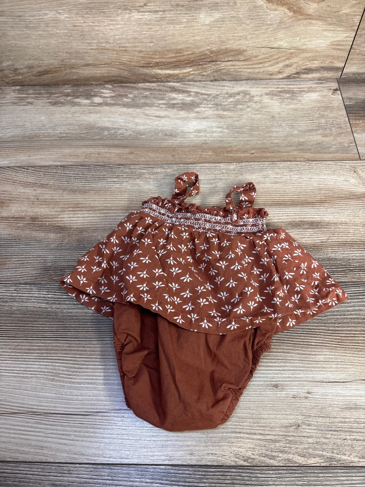 Just One You brown floral bodysuit dress for infants on a wood background