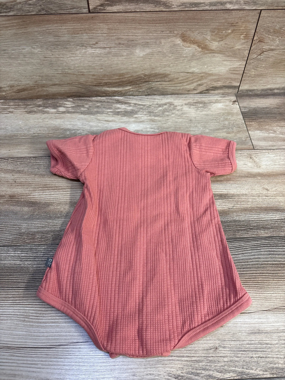 Flat lay of Modern Moments red waffle knit bubble romper showcasing textured fabric and short sleeves on a wood floor