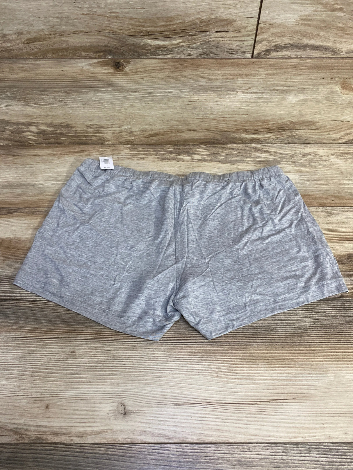 Flat lay of grey maternity modal shorts showing elastic waistband and visible size small tag on wood background