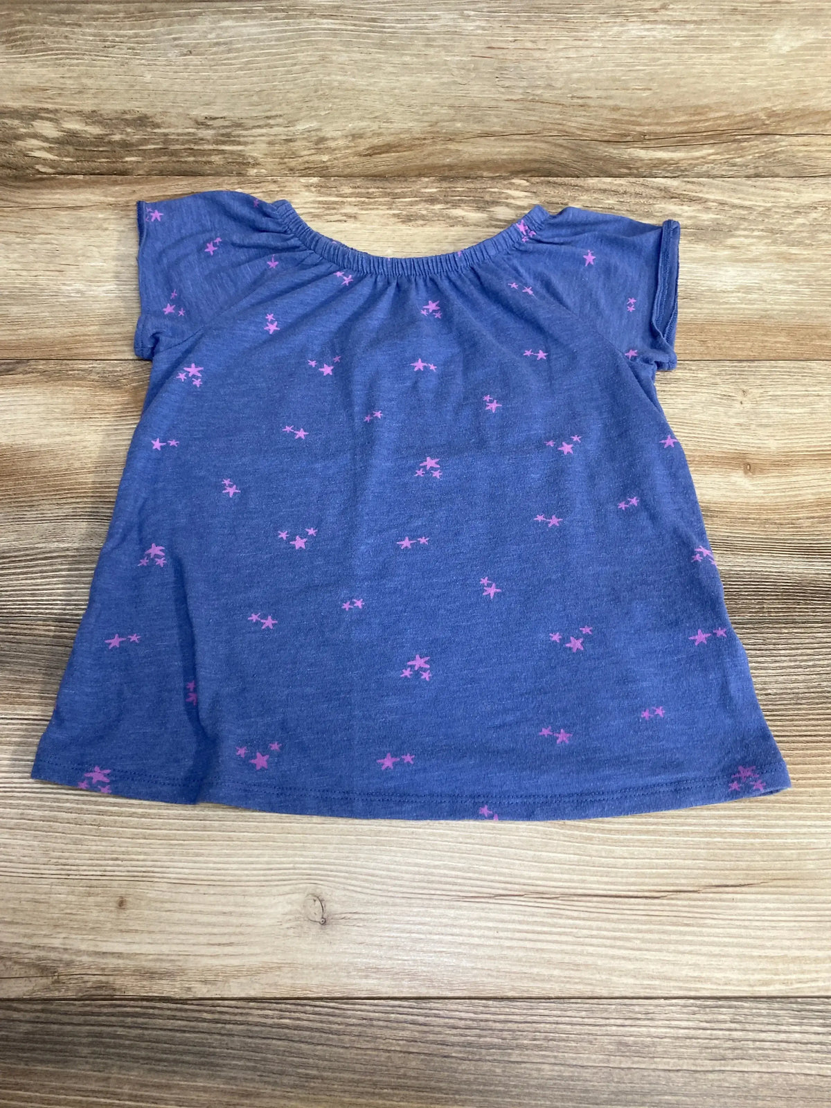 Flat-lay Cat and Jack blue toddler shirt, size 4-5T, showing small pink star print and elastic neckline on wood background
