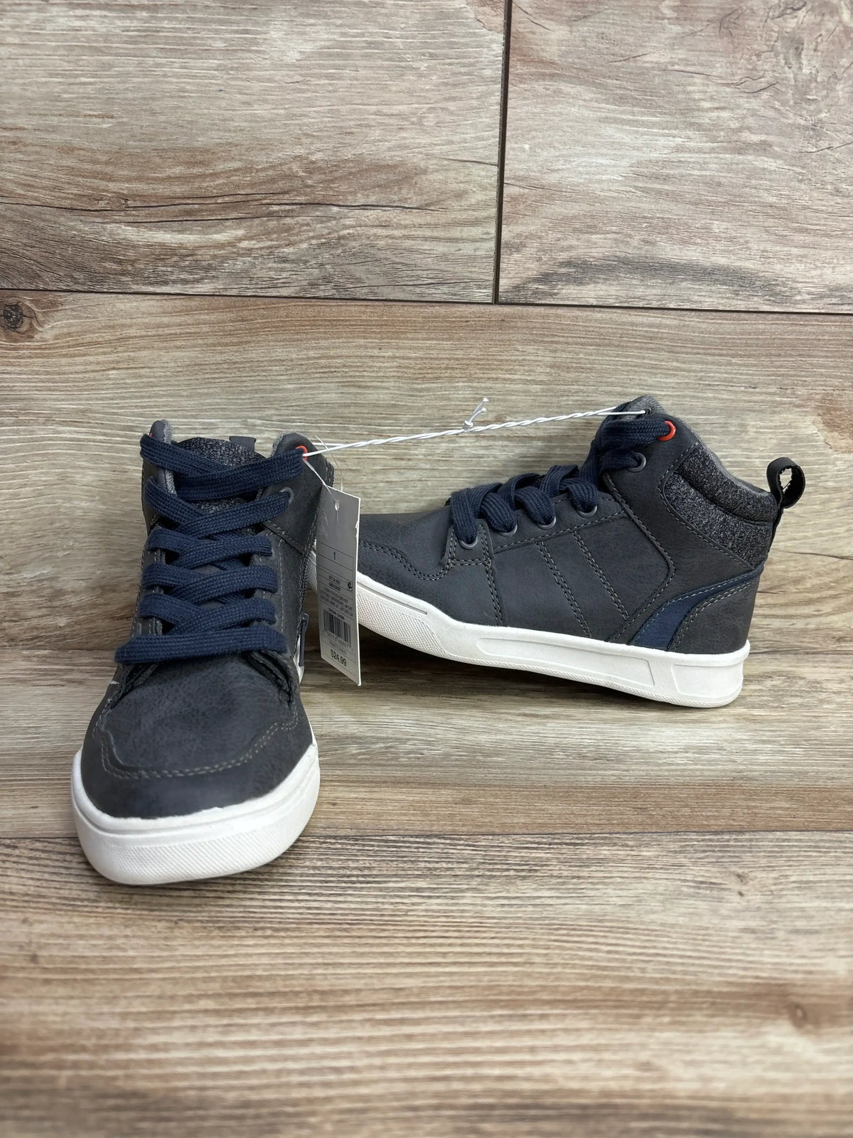 Pair of dark gray kids high-top sneakers with navy laces on wooden floor