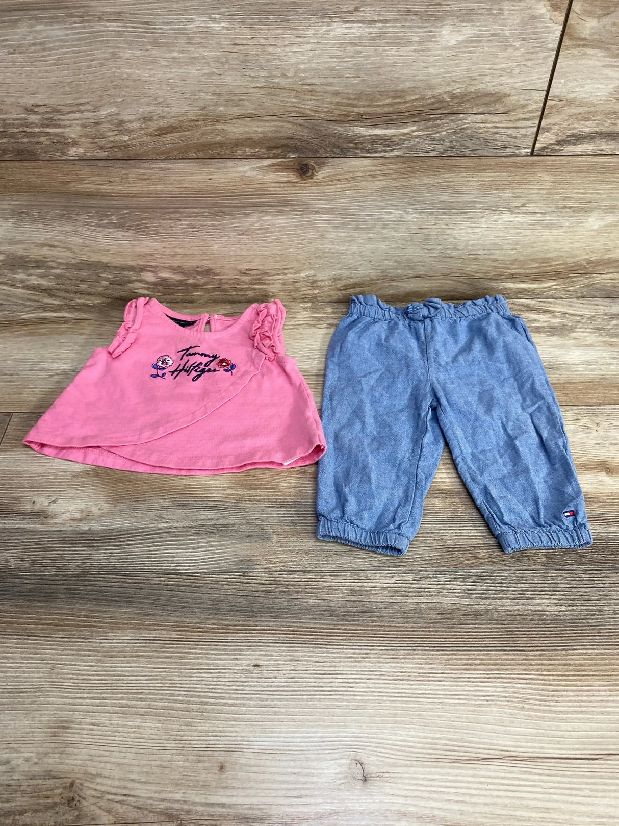 Flat lay of Tommy Hilfiger two-piece set: pink embroidered sleeveless top and chambray elastic waist pants on wood background
