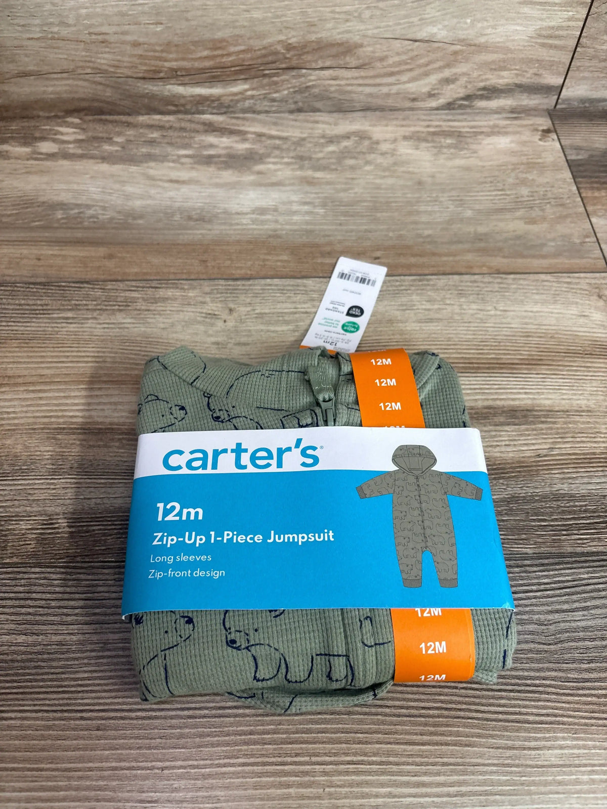 Top-down view of folded green waffle-knit hooded jumpsuit (12M) with zip-front, bear print and Carter’s label on wood