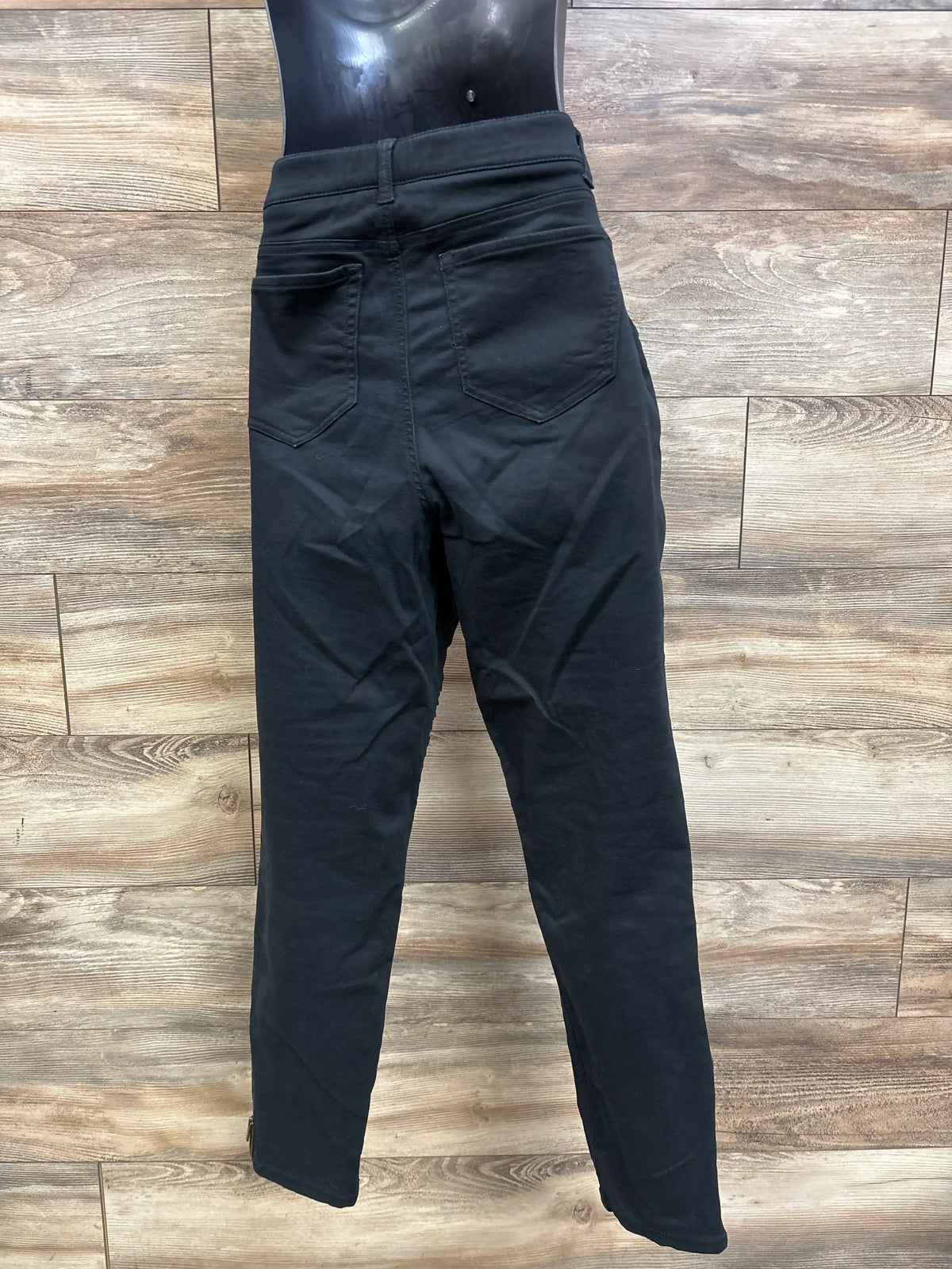 Back view of black Isabel maternity side panel jeggings on a mannequin against a wood wall.