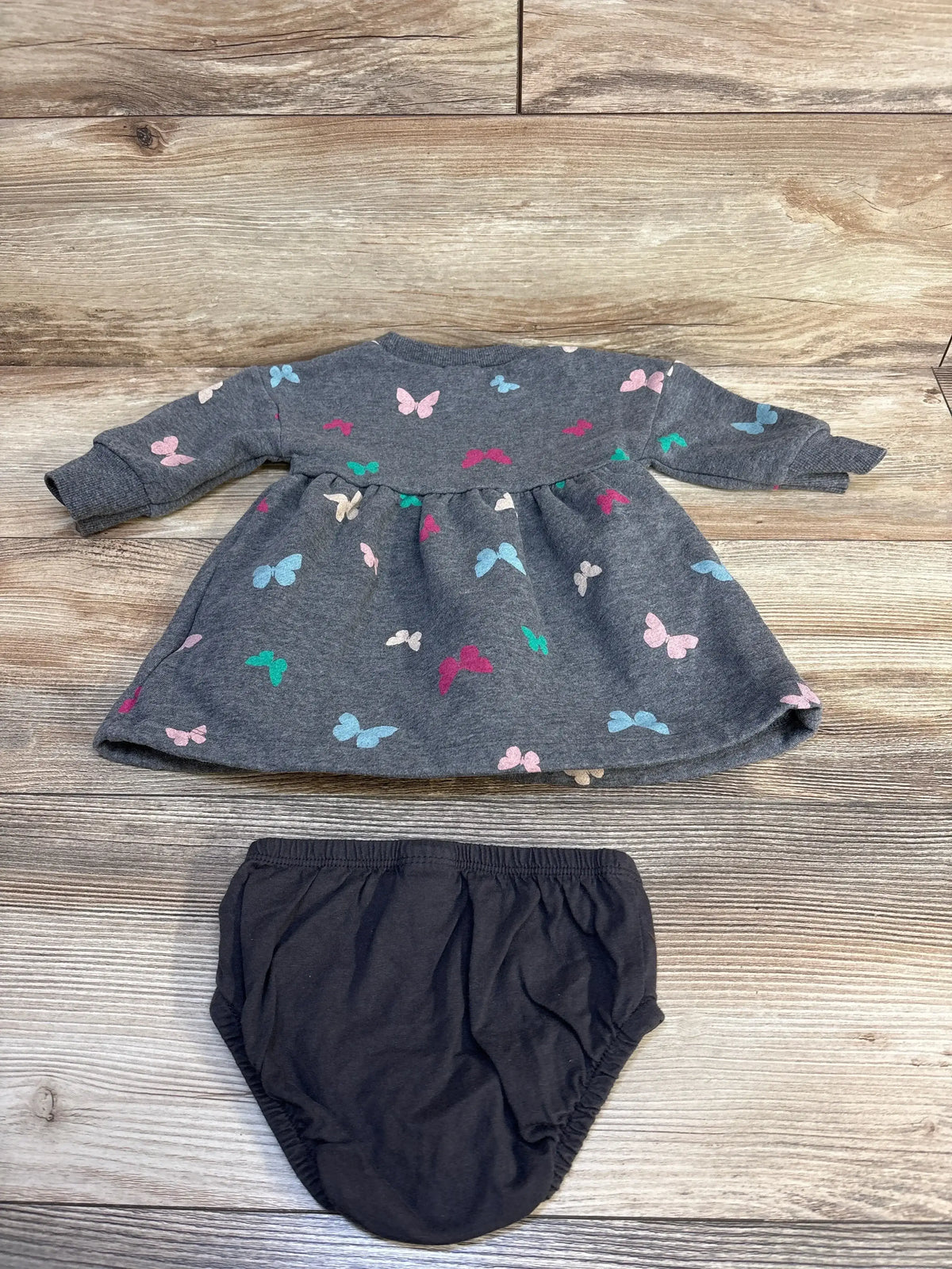 Gray baby dress with colorful butterflies and black bloomers, kids clothing set on wood floor