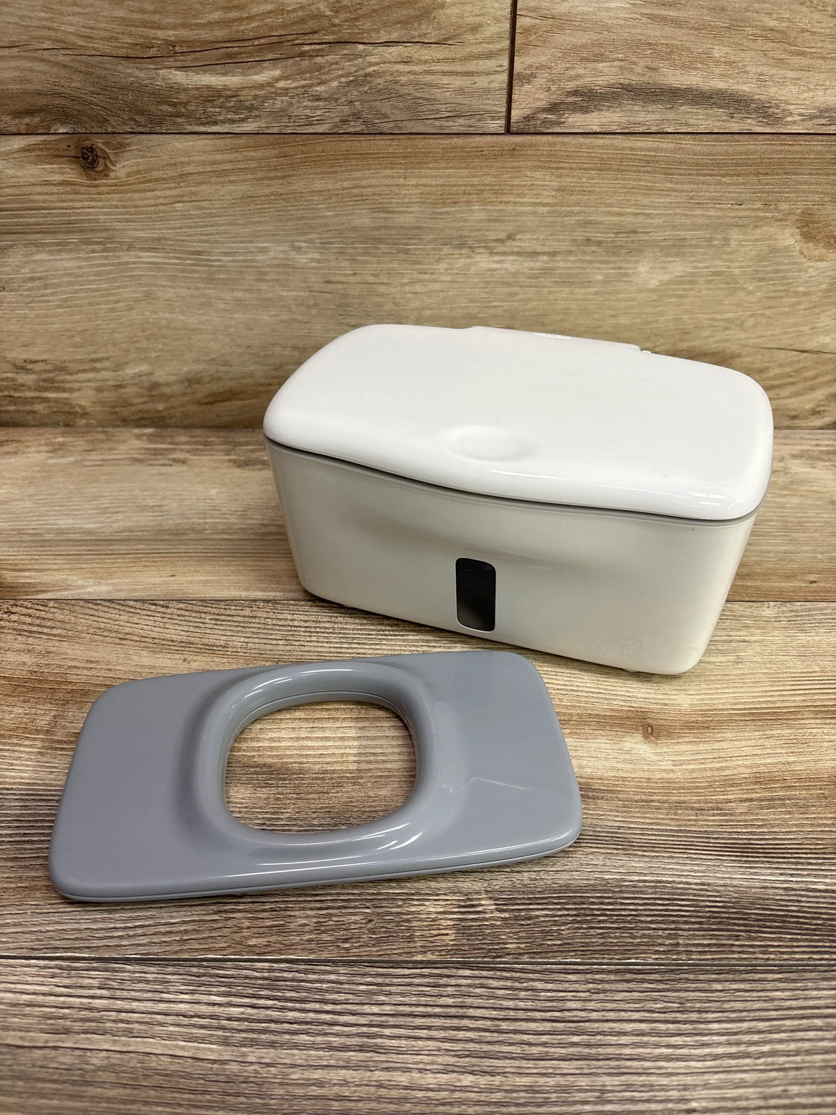 Front view of OXO Tot Perfect Pull Wipes Dispenser showcasing white body and separate gray component on a wood surface