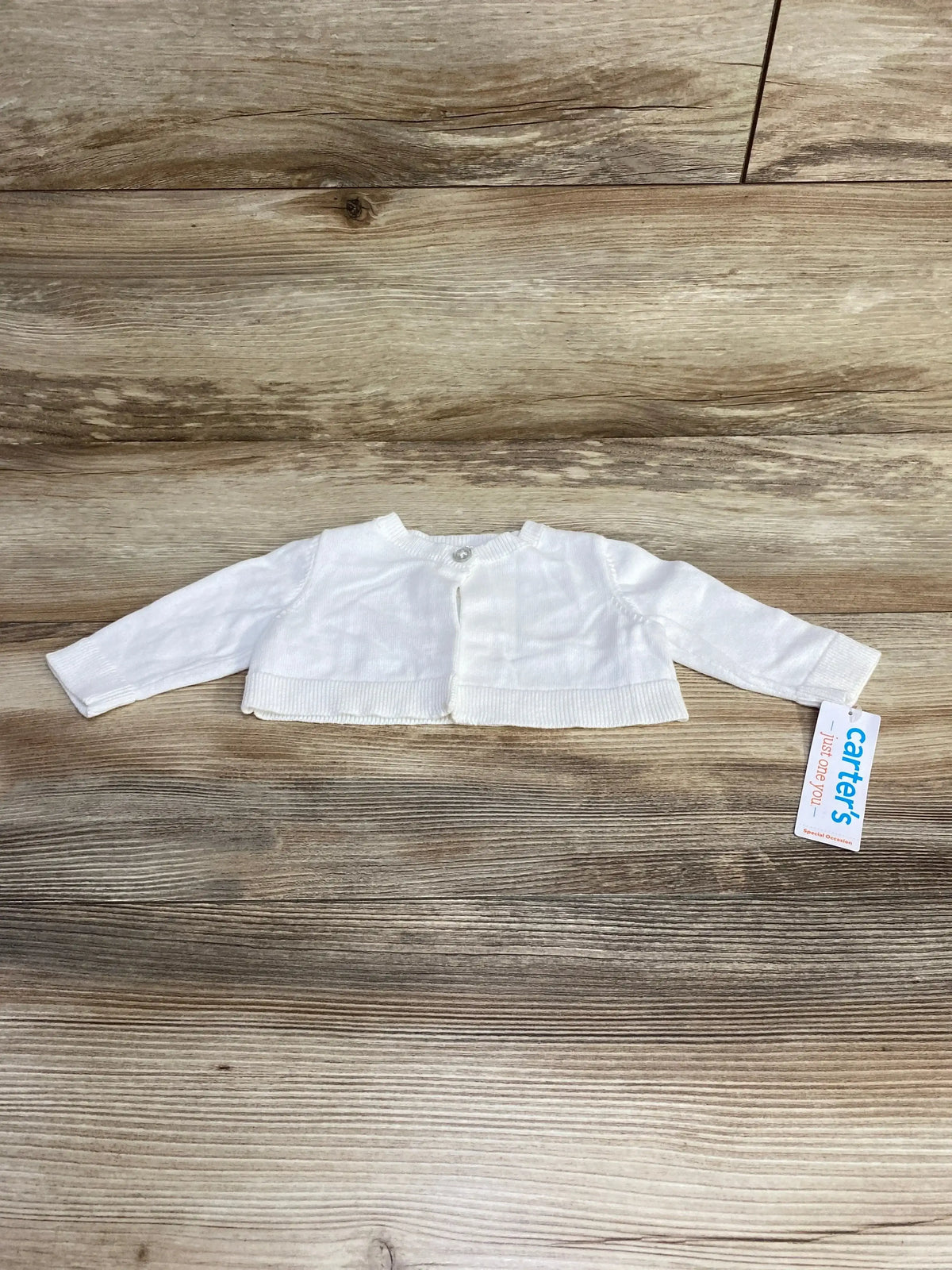 Front view of newborn white cardigan showcasing front opening and long sleeves on plain white background