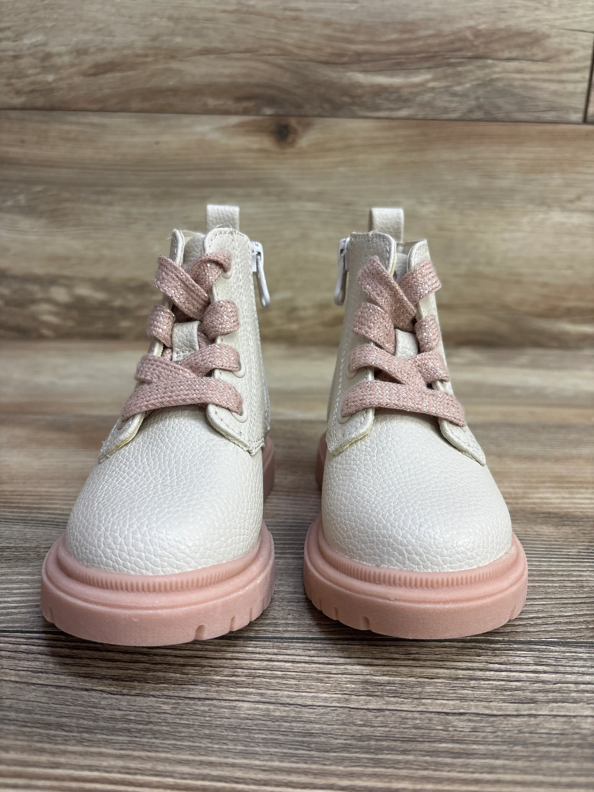 Pair of toddler white leather boots with pink soles and matching pink laces on wooden floor