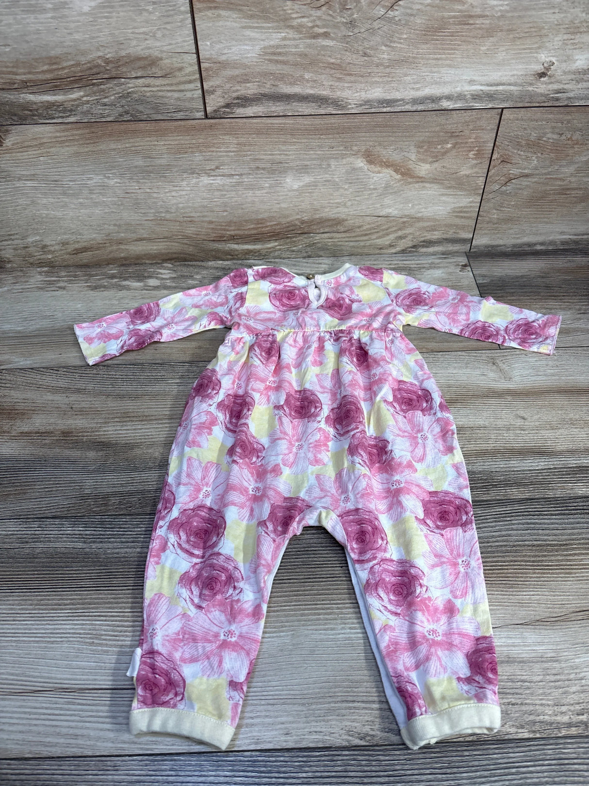 Infant floral onesie with pink and yellow flowers on wooden floor backdrop