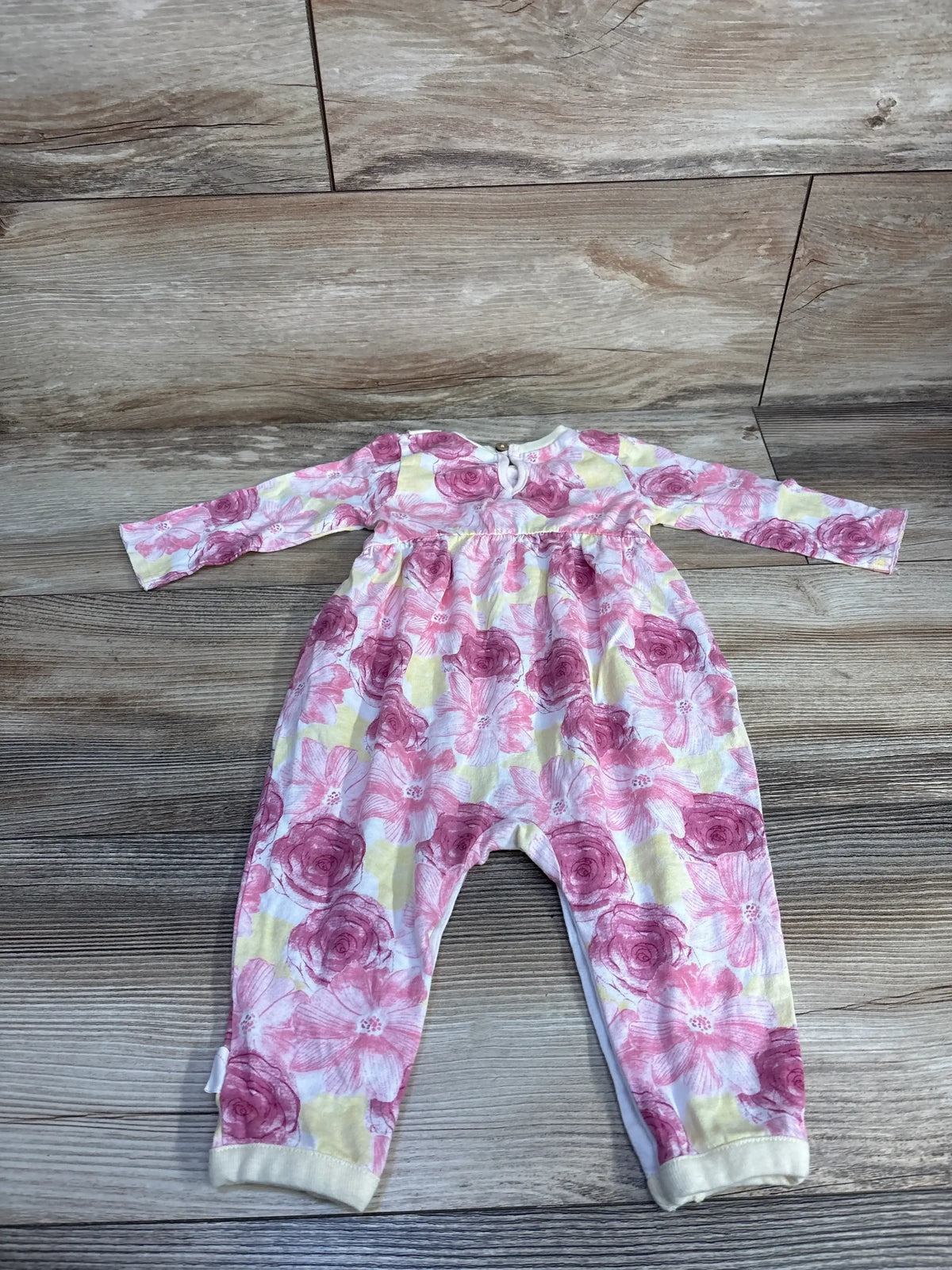 Infant floral onesie with pink and yellow flowers on wooden floor backdrop