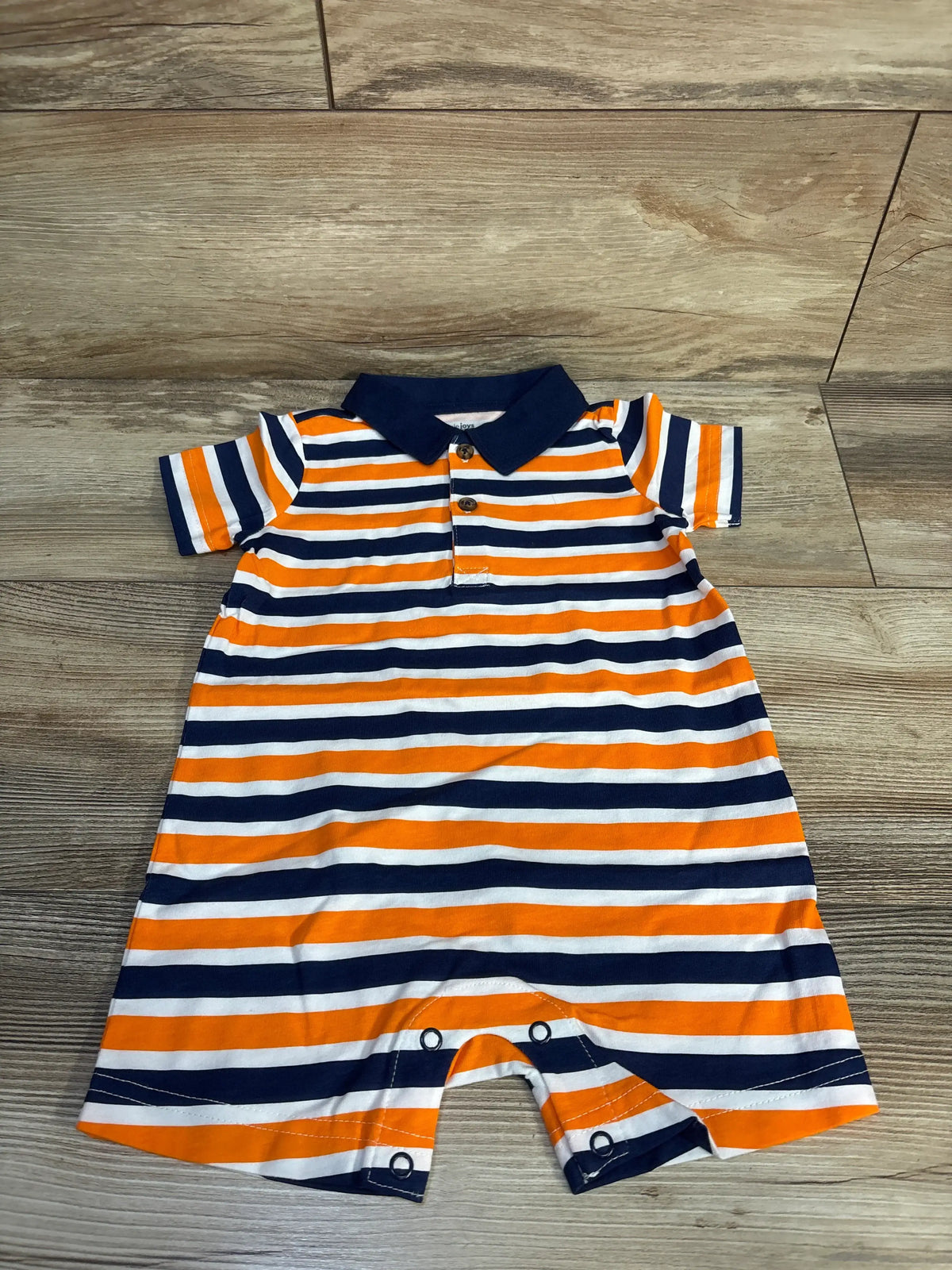Front view of Simple Joys striped polo shortie romper with navy, orange, and white stripes on a wood floor