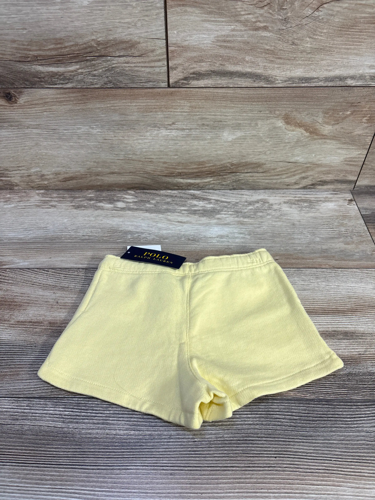 Front view of Longwood Yellow Polo Ralph Lauren drawstring shorts, size 4T, with elastic waist on wood-grain background