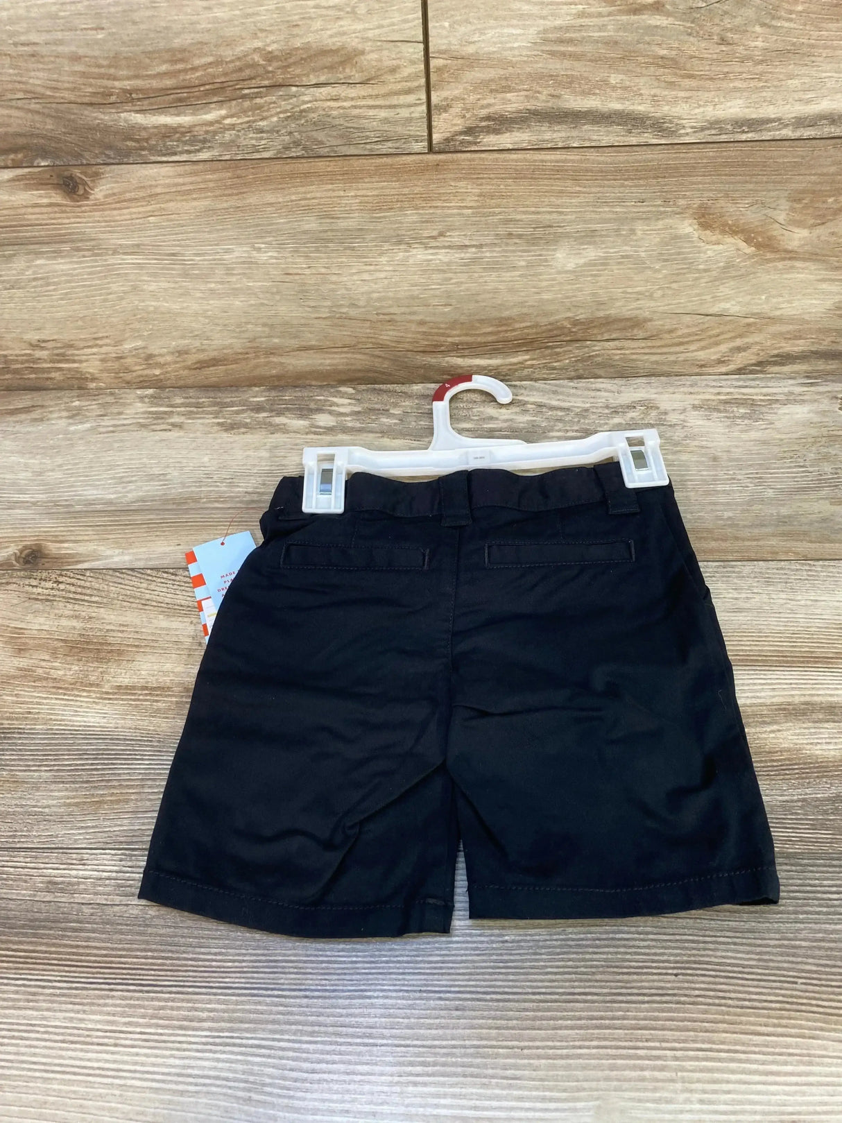 Back view of NEW Cat and Jack School Uniform Shorts in black showcasing belt loops back pockets and hangtag on wood plank floor