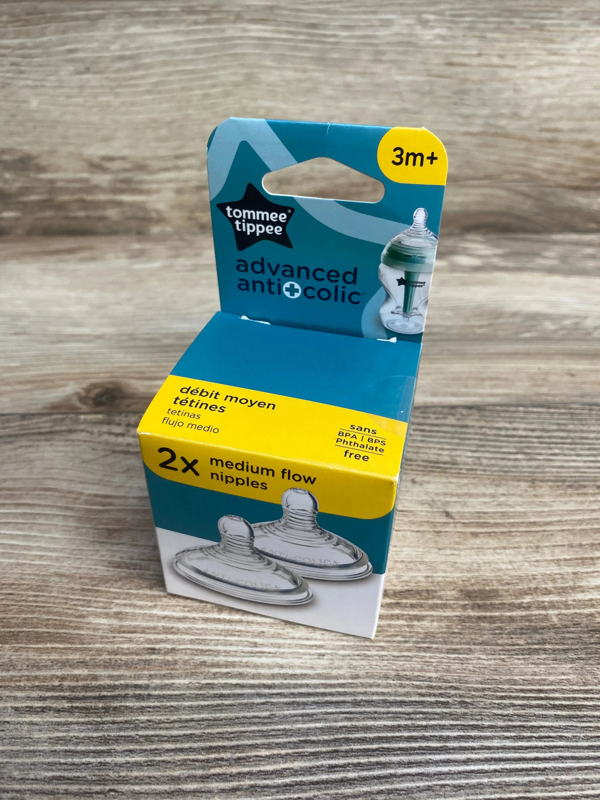 Three-quarter view of Tommee Tippee Advanced Anti‑Colic medium‑flow nipple 2‑pack box showing '2x medium flow nipples' and '3m+' on wood surface