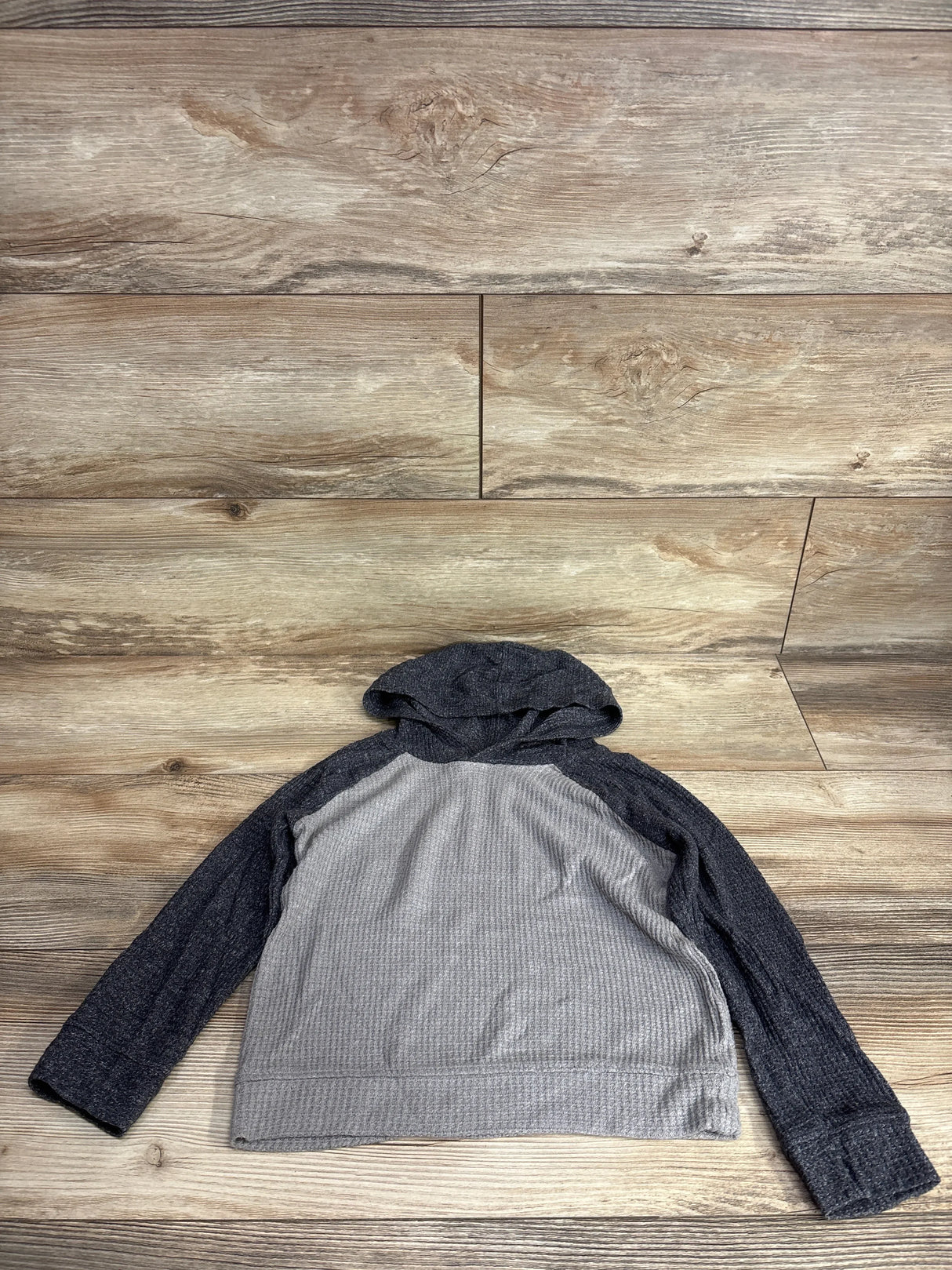 Kids' long sleeve gray and black waffle knit hooded shirt on wood background