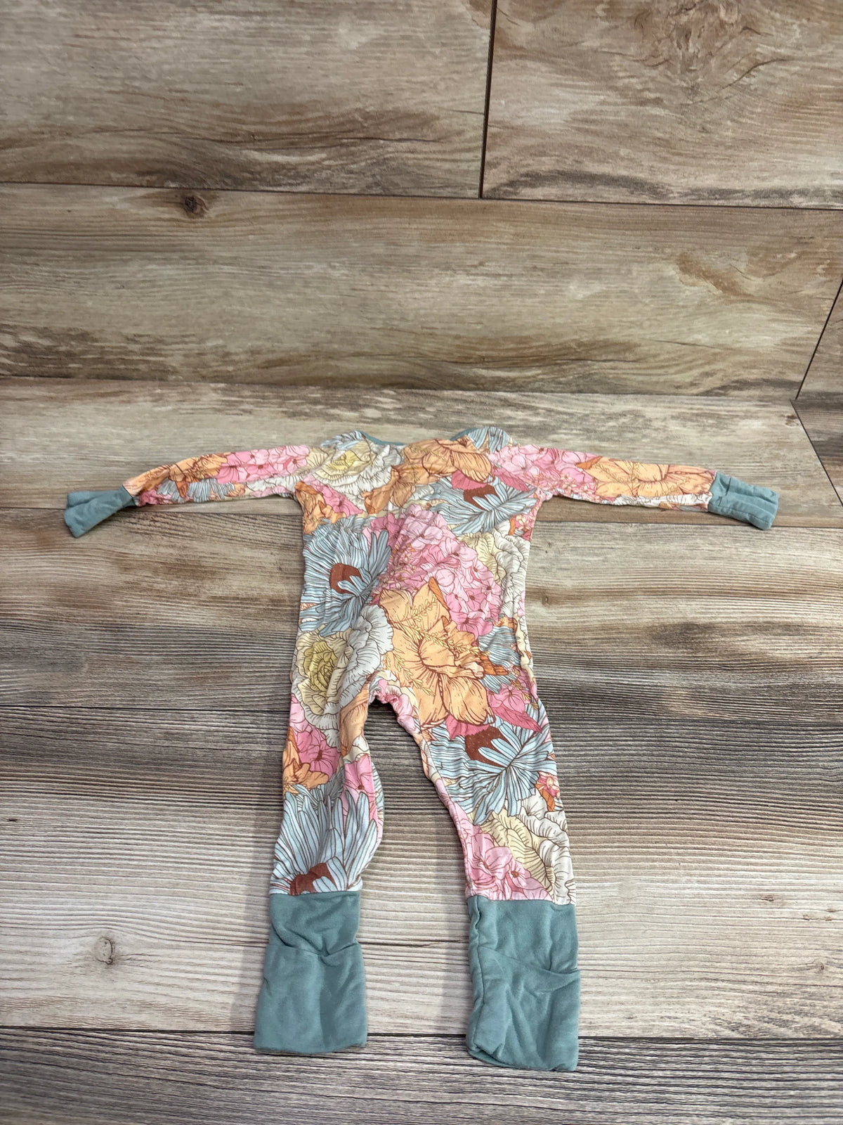 Top view of Miozing Vintage Floral Bamboo Sleeper in green, size 0 to 3 months, with foldover cuffs on wood floor