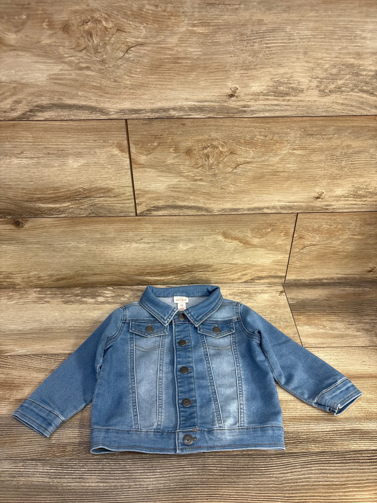 Front view of Cat & Jack blue denim jacket showcasing button front, pointed collar, and chest pockets on wood background