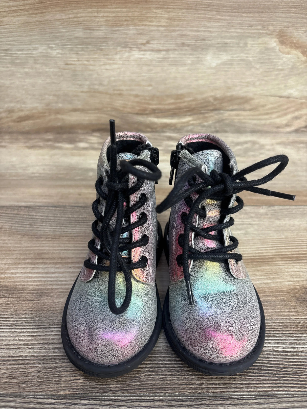 Iridescent toddler lace-up boots with black laces on wood background