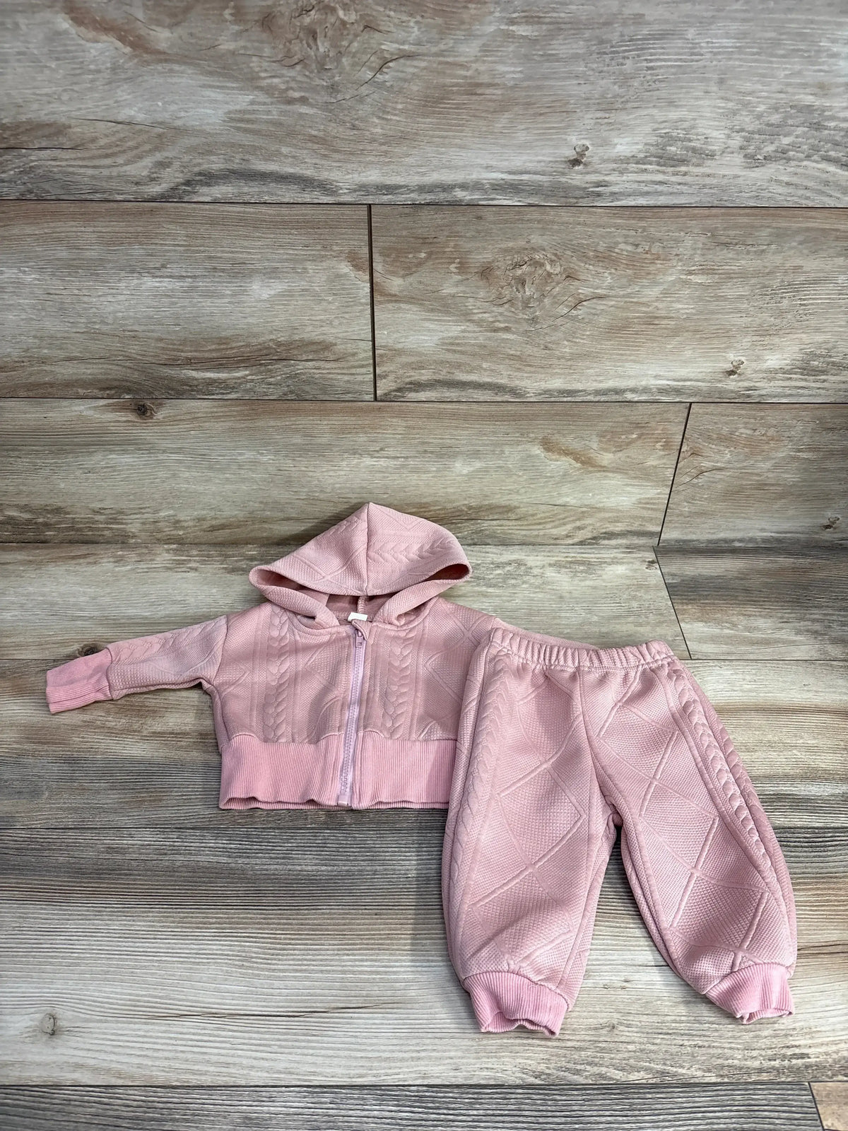 Pink knit baby hoodie and matching pants set laid out on wooden floor, kids resale clothing