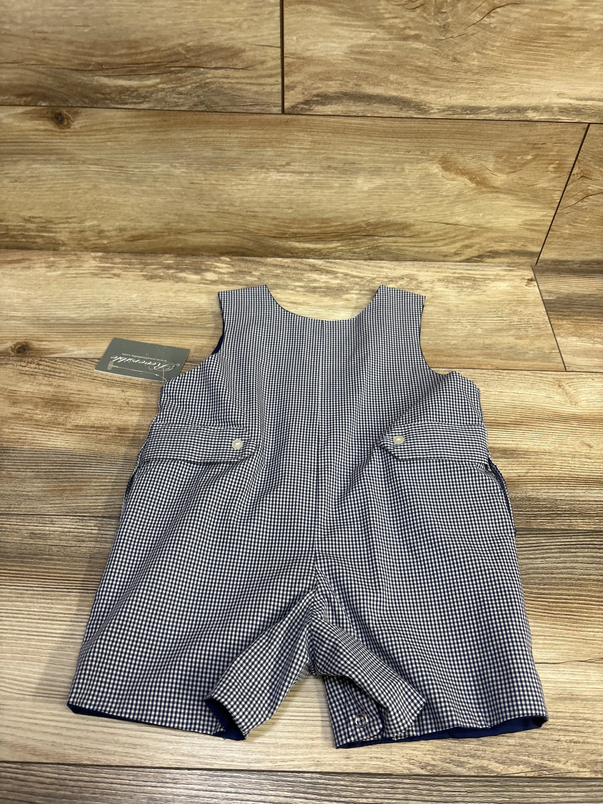 Front view of Sir John by Rosalina pumpkin embroidered gingham romper showcasing flap pockets on a wood floor