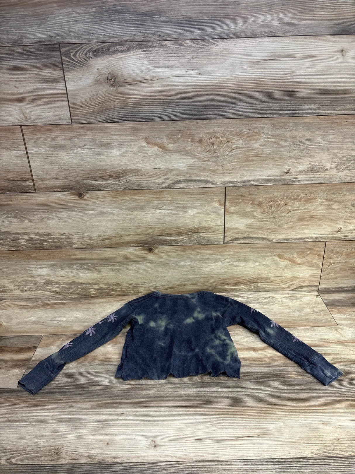 Dark blue tie-dye long sleeve cropped sweater with pink palm tree designs on sleeves on wood background