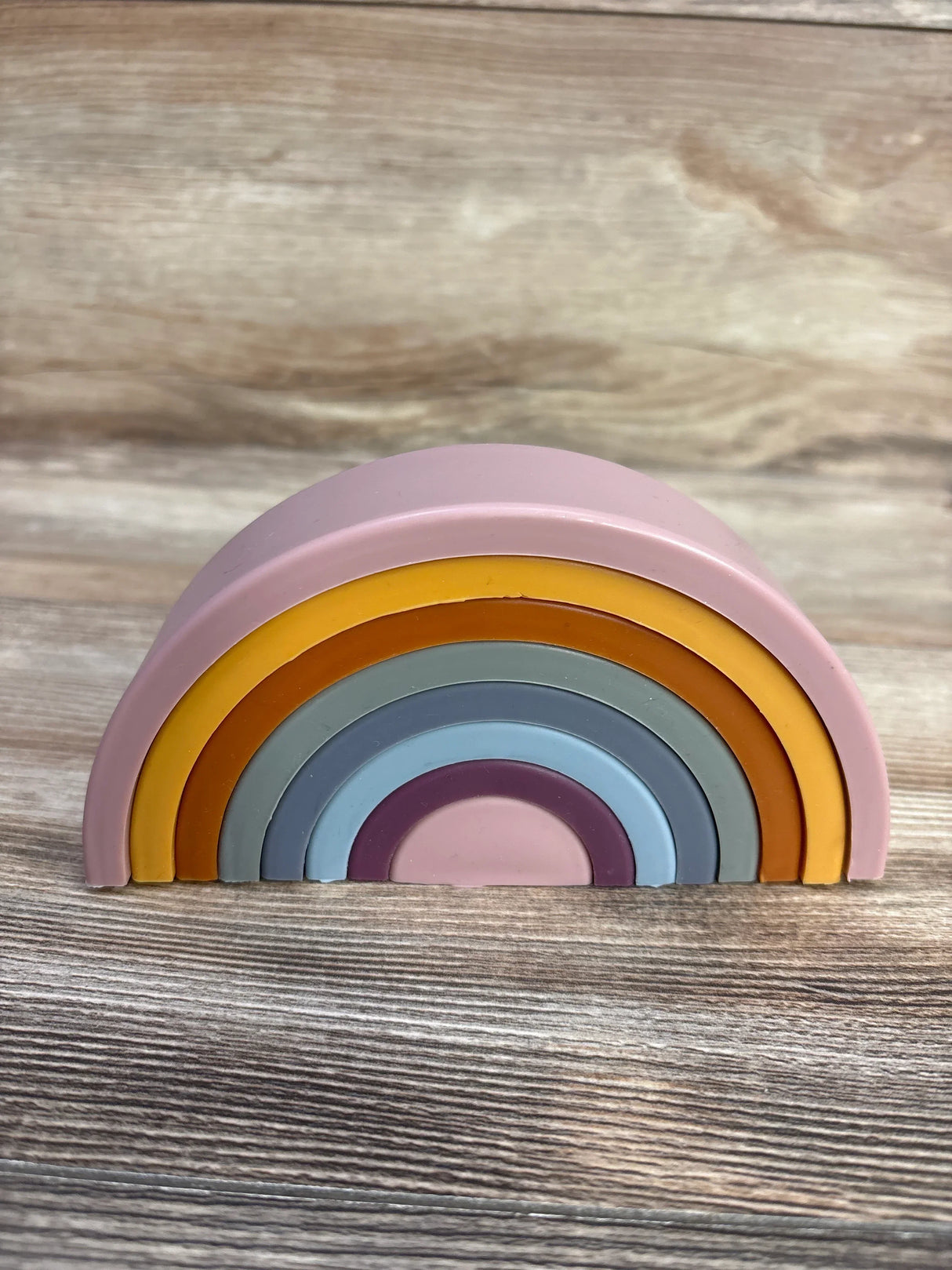 Front view of Twinkle Twinkle Little One silicone dusty rainbow stacker with nested pastel silicone arches on light wood