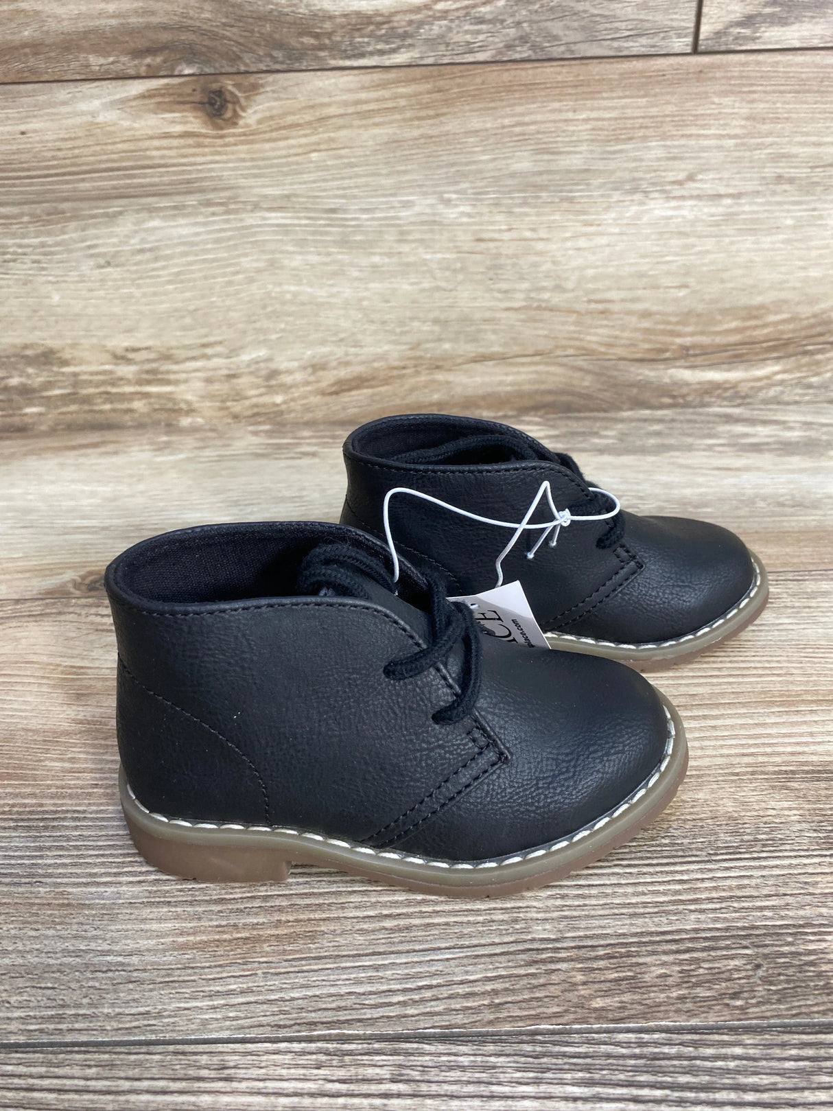Black toddler lace-up boots with brown soles on wooden background