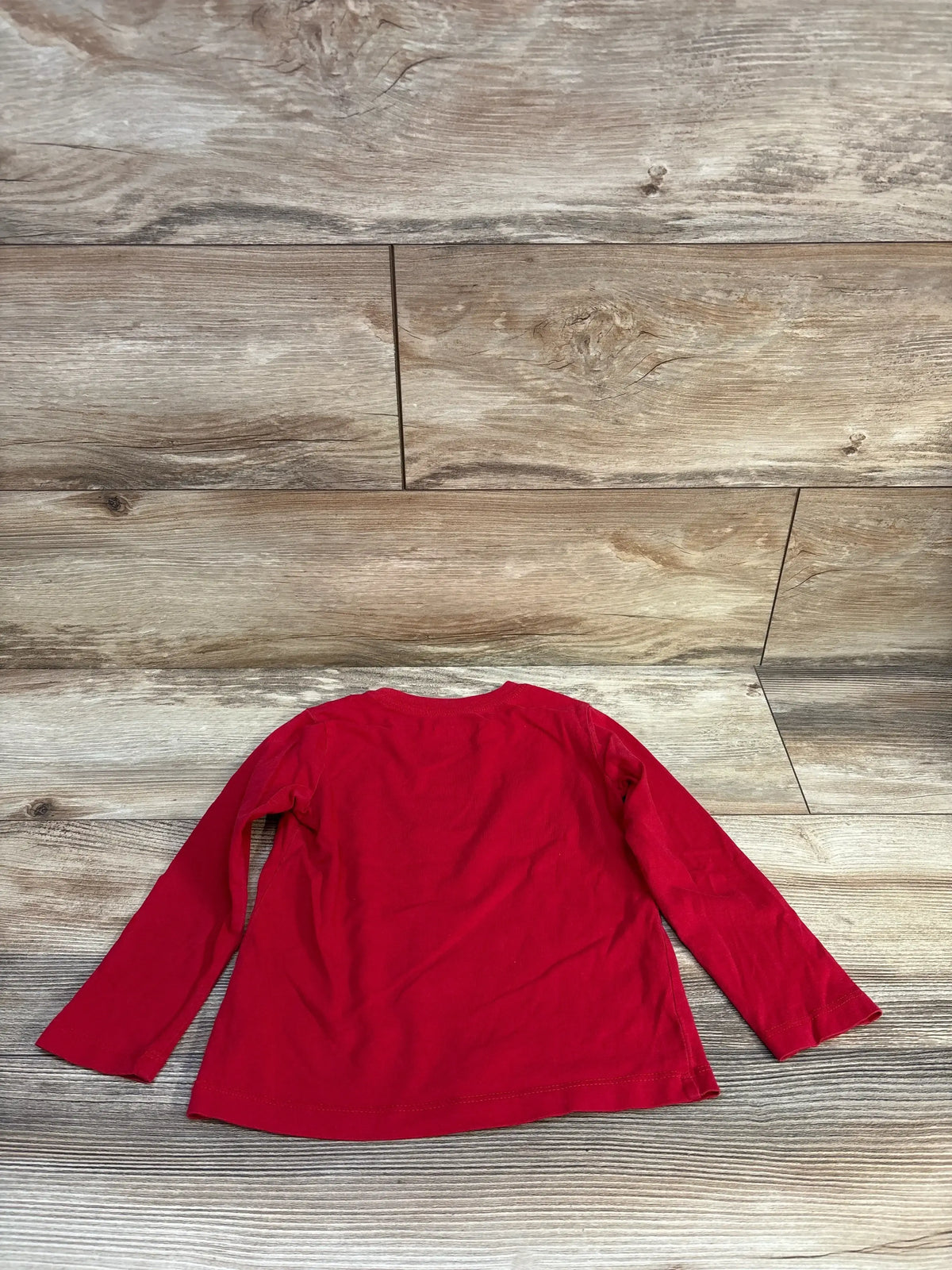 Red long sleeve kids shirt on wood background, gently used children's clothing